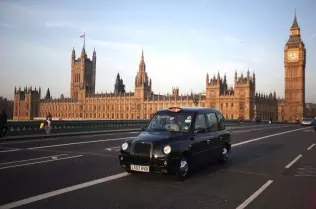Londyńska taksówka przed siedzibą brytyjskiego parlamentu